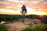 Cyclist Riding the Bike on the Mountain Rocky Trail at Sunset