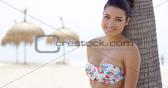 Attractive young woman leaning on palm tree