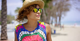 Grinning woman in sunglasses and hat near ocean