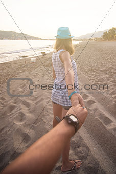 Girl holding a hand man on the beach