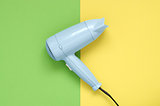 Blue hair dryer on green and yellow background