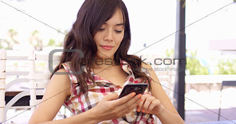 Young woman relaxing on a patio with a mobile