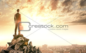 Young businessman standing on edge of rock