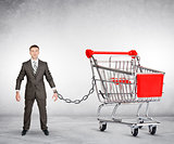 Businessman chained to shopping cart