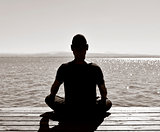 young man meditating outdoors seen from behind