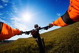 Hands in orange jacket holding handlebar of a bicycle