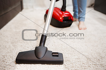 Woman doing cleaning in room, vacuuming white carpet