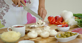 Housewife preparing dinner slicing fresh mushrooms