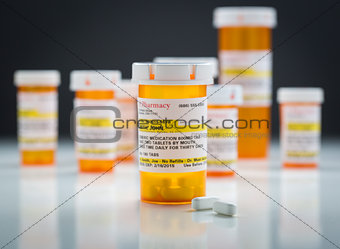 Medicine Bottles and Pills on Reflective Surface With Grey Backg