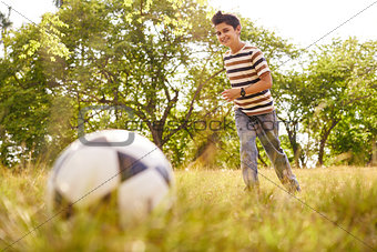 Young boy playing soccer game hitting ball
