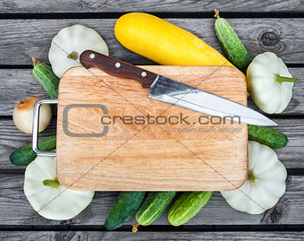 Cutting board, knife, fresh vegetables on wooden table.  Top vie