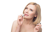 Beautiful middle aged woman applying lipstick