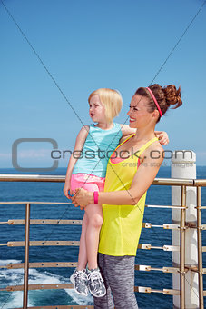 Happy mother and child in fitness outfit on embankment