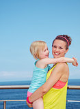 Happy mother and child in fitness outfit hugging on embankment