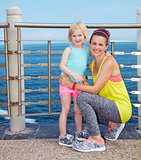 Portrait of mother and child in fitness outfit on embankment