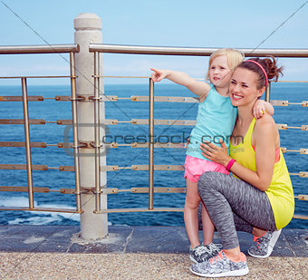 Fitness mother and child on embankment pointing on something