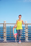 Happy mother and child in fitness outfit standing on embankment