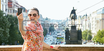Smiling young woman taking selfie with digital camera in Prague