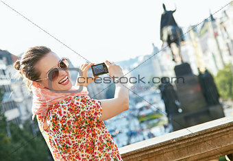 Happy young woman taking photos with digital camera in Prague