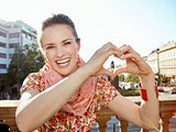 Smiling young woman showing heart shaped hands in Prague