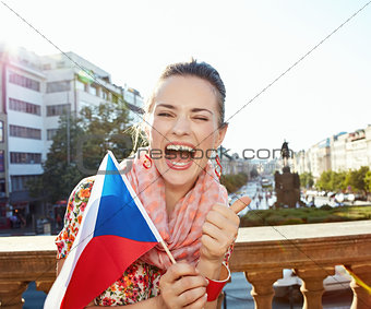 Happy woman with Czech flag showing thumbs up. Prague