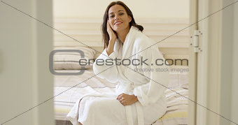 Gorgeous woman in robe sitting on bed