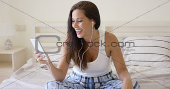 Happy woman listening with ear buds and tablet