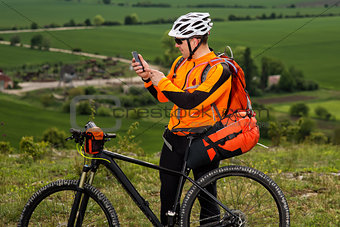 Young Cyclist In Orange Shirt Checks His Phone