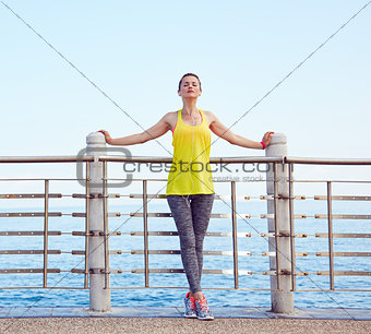 Woman in fitness outfit relaxing after workout at embankment