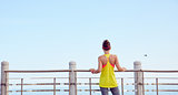young woman in fitness outfit standing at embankment
