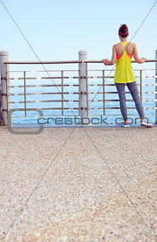 young woman in fitness outfit standing at embankment
