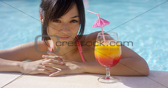Happy young woman eyeing a large tropical cocktail