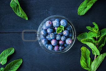 Blueberry in a glass bowl on the blue wooden table