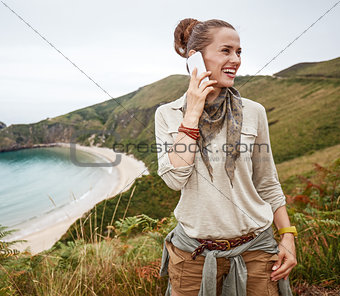 hiker looking aside and using mobile phone in front of ocean