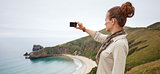 woman hiker taking photo in front of ocean view landscape