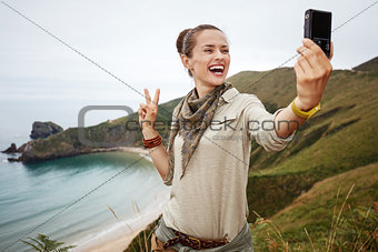 woman hiker taking selfie with digital camera and showing victor