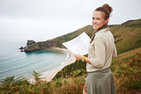 happy woman hiker with map in front of ocean view landscape