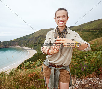 hiker showing hashtag gesture in front of ocean view landscape