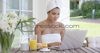 Young woman using a laptop while having breakfast