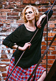 Grunge fashion: cute young woman in checkered skirt and jacket standing on ladder
