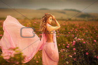 beautiful sexy girl in a pink dress standing in the garden roses