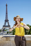 smiling woman showing heart shaped hands in Paris, France
