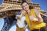 Happy mother and daughter travellers showing thumbs up in Paris