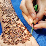 young woman mehendi artist painting henna on the hand