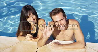 Smiling couple standing in clear pool wave