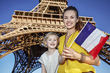 mother and daughter tourists showing flag against Eiffel tower