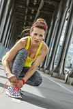 woman jogger tying shoelaces on Pont de Bir-Hakeim bridge, Paris