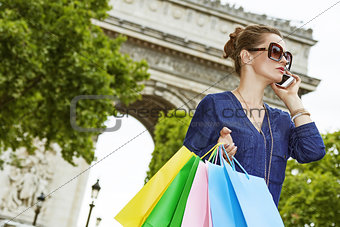 Woman with shopping bags speaking on cell phone, Paris