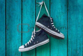 pair of blue men's sports sneakers hanging from a nail on the wa