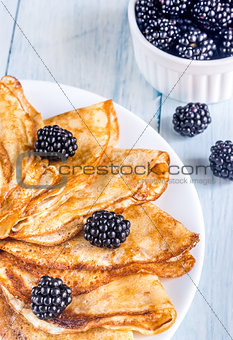 Crepes with blackberries on the wooden table